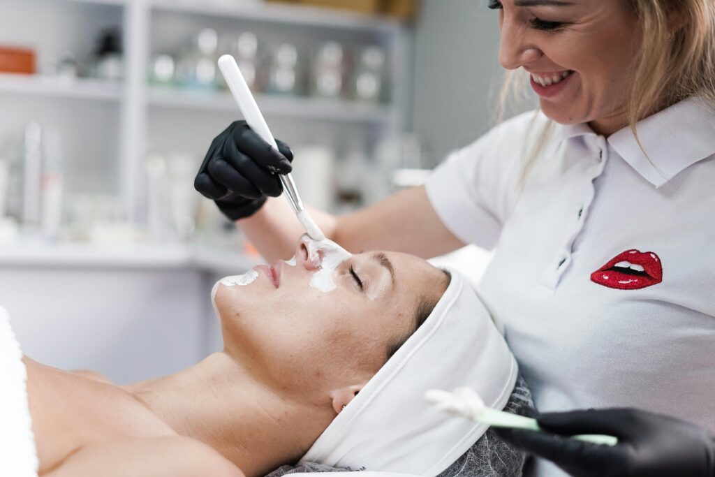 A beautician applying a face mask to a client in a salon, highlighting skincare and relaxation.